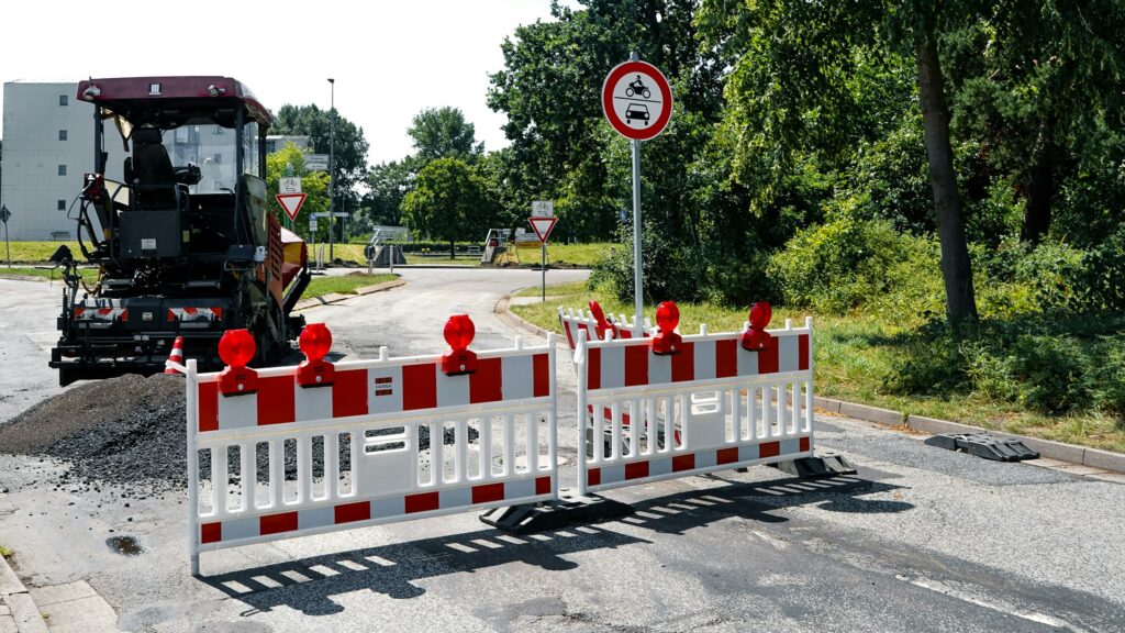 Bagger und Absperrungen an einer Straßenbaustelle, Symbolbild für Kanalbauarbeiten