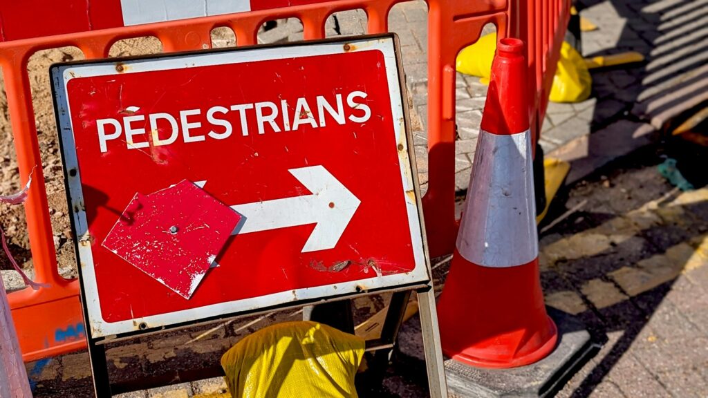 Symbolbild einer Vollsperrung: Schild für Fußgänger neben einem Verkehrskegel an einer Baustelle