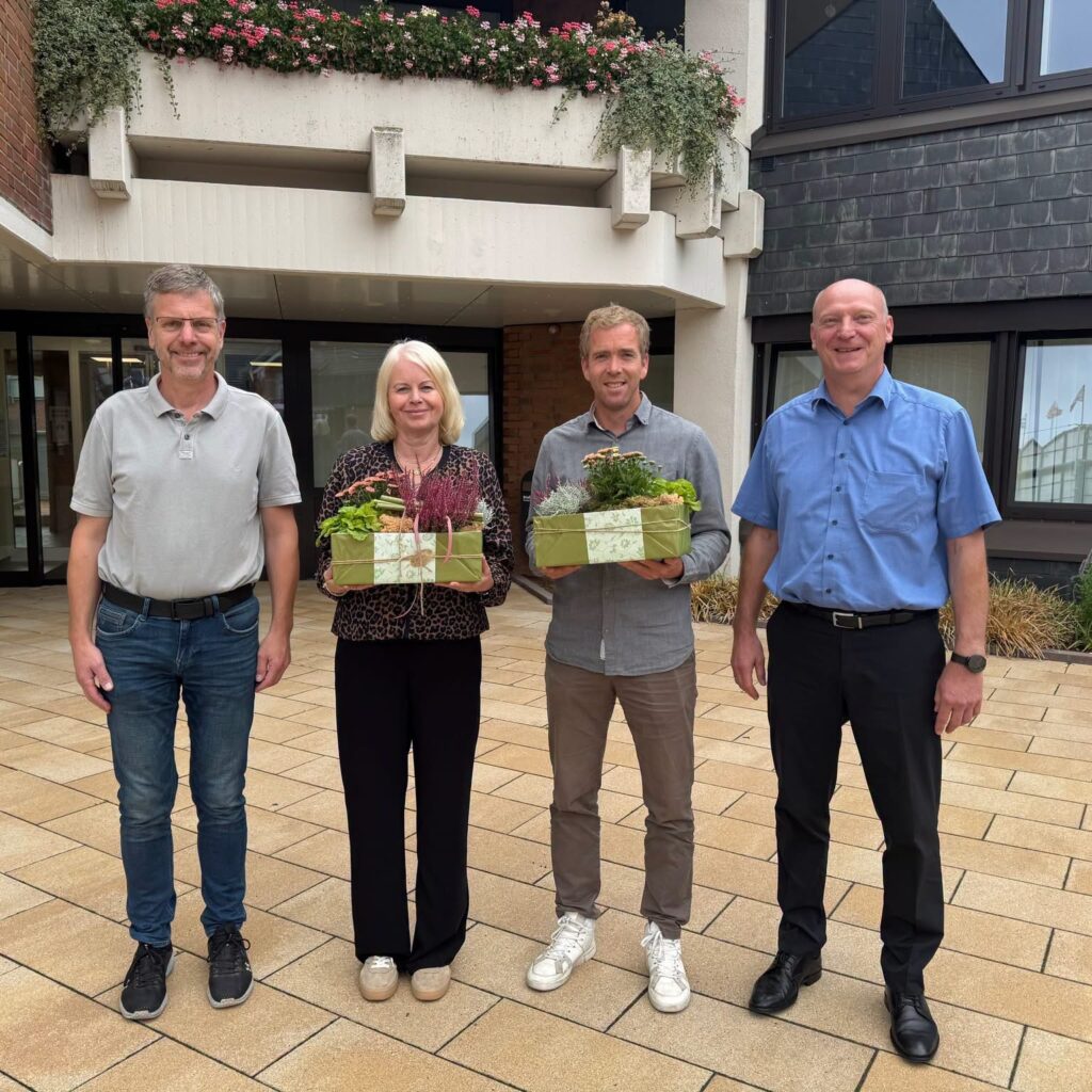 Godehard Ritz, Brigitte Bekel, Philipp Mey und Mathias Brinker stehen mit Blumengeschenken vor dem Rathaus der Samtgemeinde Freren