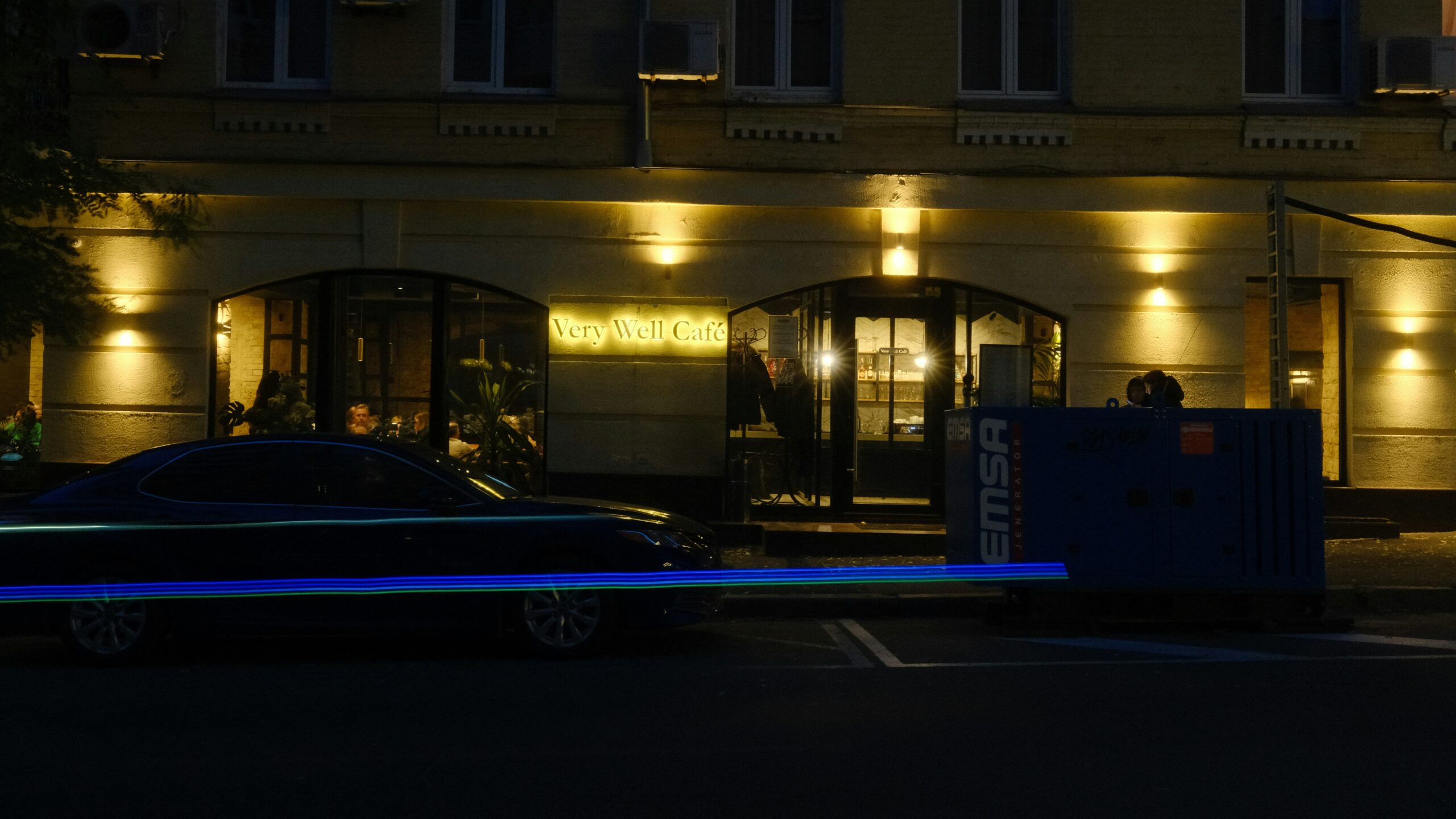 Dunkles Fahrzeug bei Nacht vor beleuchtetem Gebäude