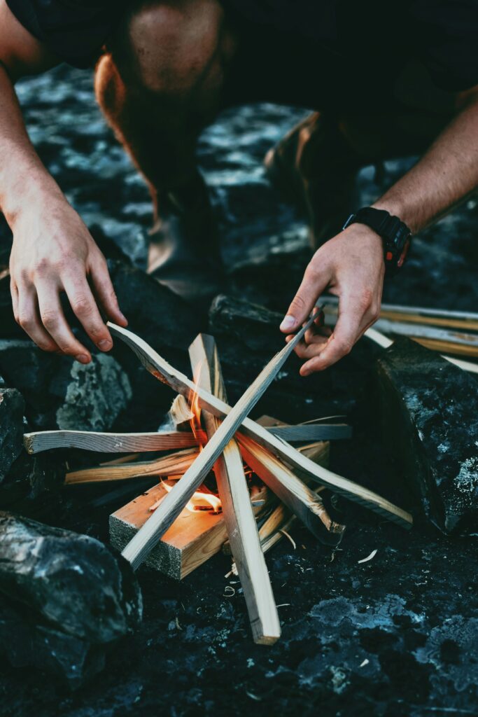 Person entzündet mit traditioneller Technik ein Feuer im Freien (Symbolbild)