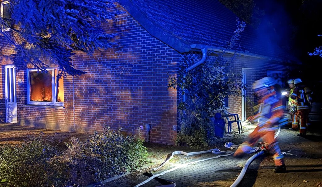 Feuerwehrfahrzeuge mit Blaulicht auf einer Straße in Werlte während des Löscheinsatzes bei Nacht