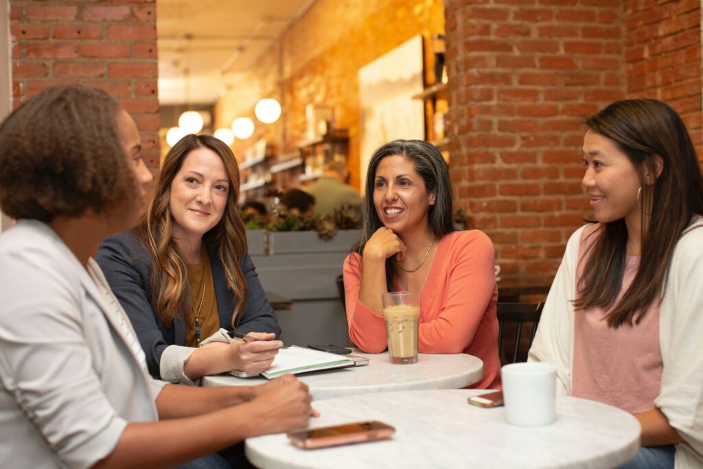 Vier Frauen sitzen im Café an einem Tisch und besprechen sich