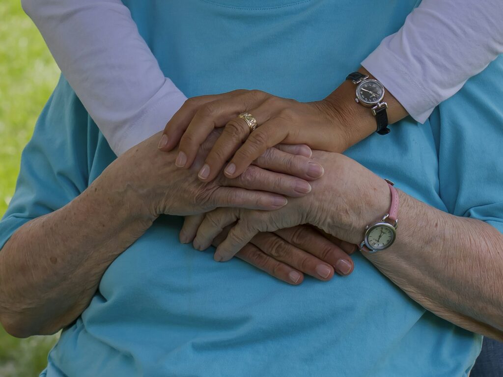Eine jüngere Hand hält die Hand eines älteren Menschen