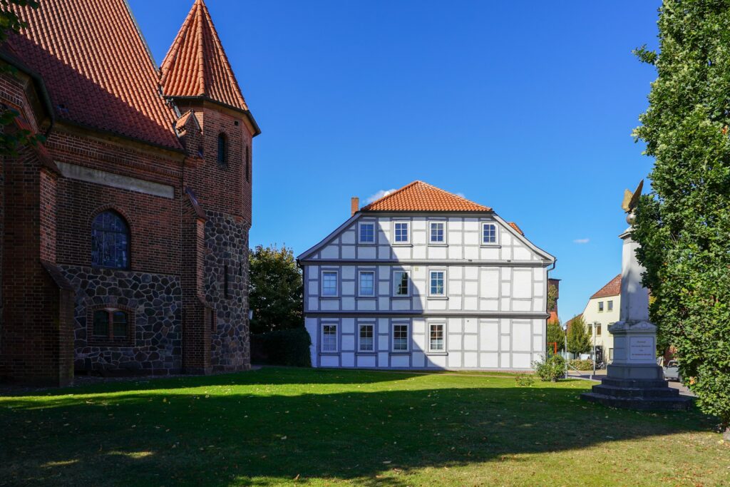 Historisches Fachwerkhaus neben einer Backsteinkirche (Symbolbild)