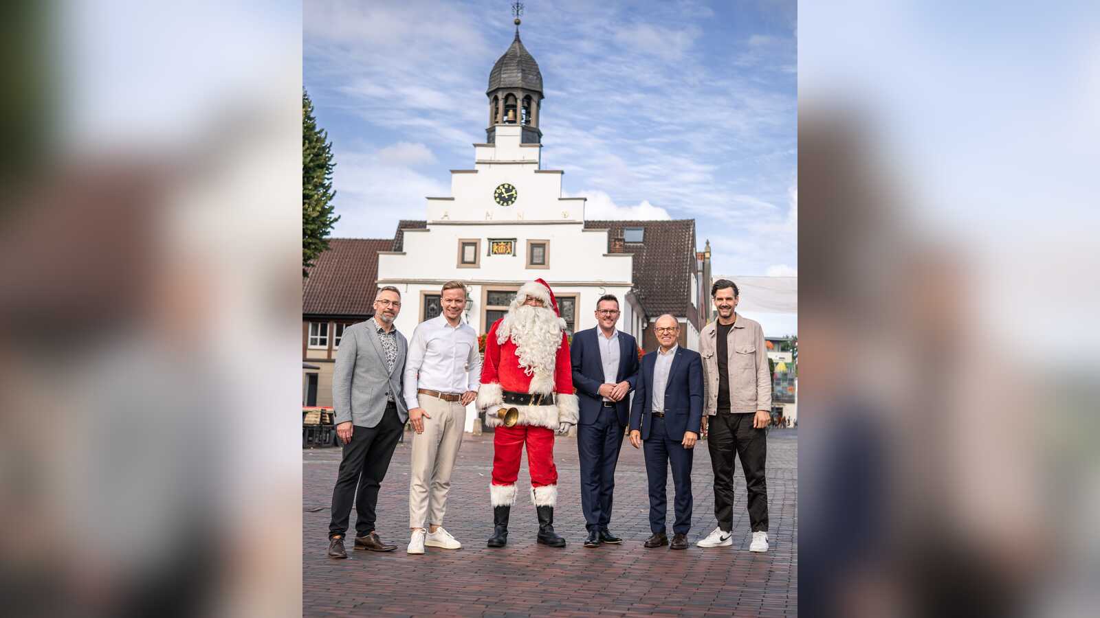 Der Weihnachtsmann steht mit fünf Männern vor dem historischen Rathaus in Lingen