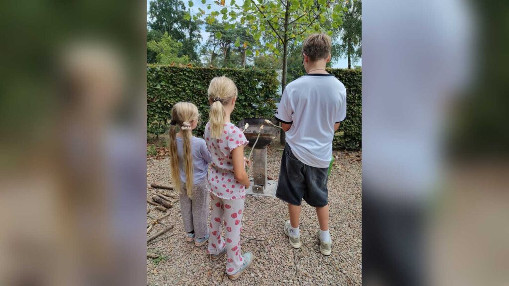 Kinder sitzen am Lagerfeuer und bereiten Stockbrot zu, Kinderexpertenrat Coesfeld