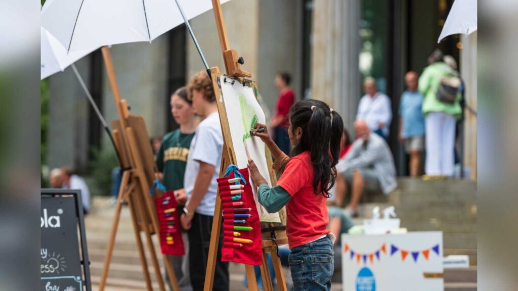 Kinder und Erwachsene zeichnen an Staffeleien unter Sonnenschirmen vor der Kunsthalle Bremen