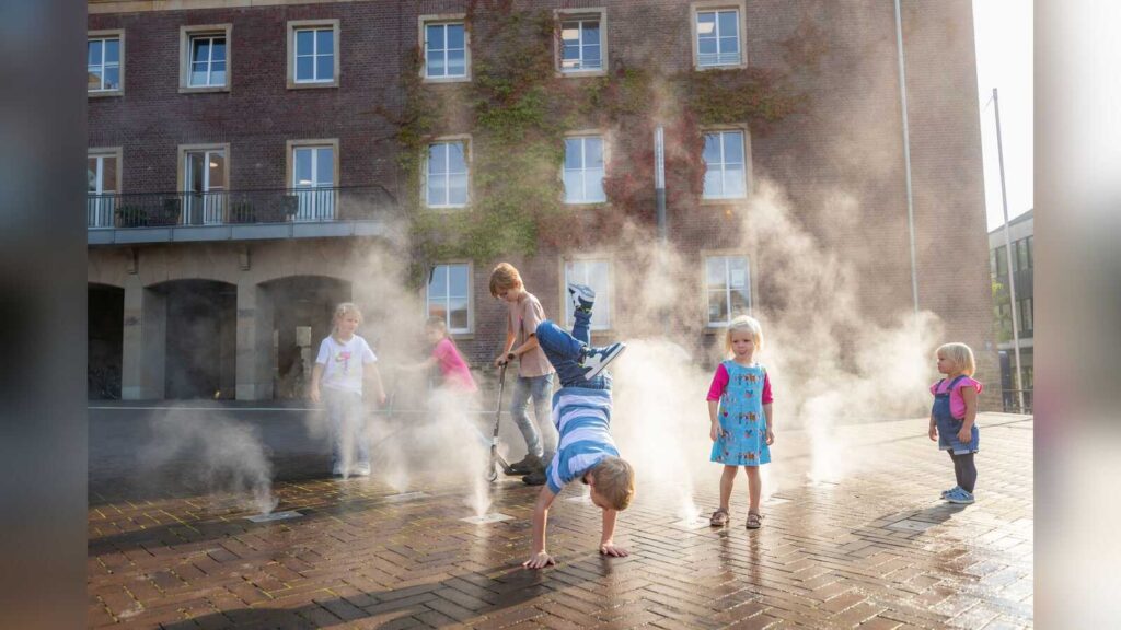 Kinder spielen im Nebel des Nebeldüsenfelds auf dem Marktplatz in Dülmen