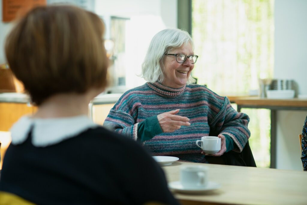 Zwei Frauen sitzen im Gespräch an einem Tisch
