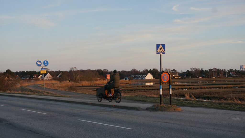 Radfahrer auf einer Straße durch Felder und an Häusern vorbei, Symbolbild zum neuen Radweg an der K 60 in Senden