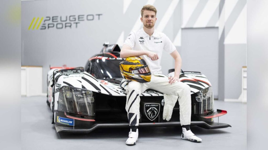 Robert Shwartzman sitzt auf der Motorhaube des PEUGEOT 9X8 vor dem PEUGEOT-Sport-Logo