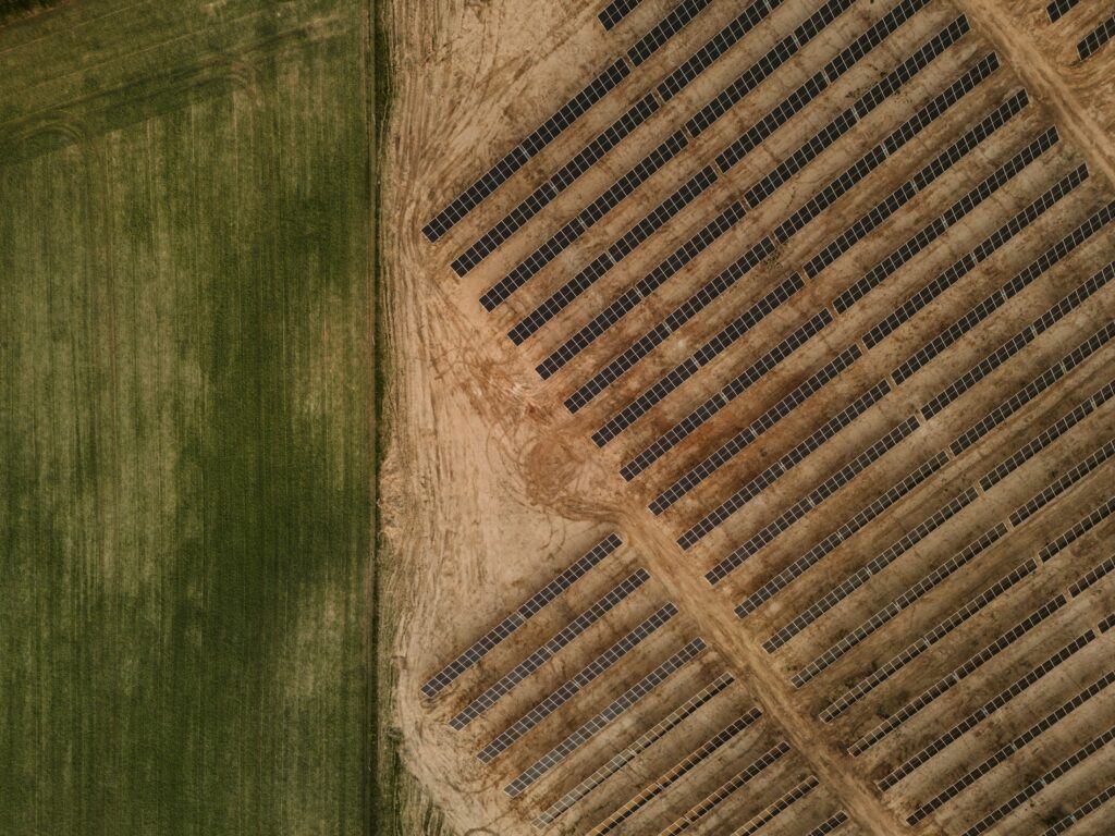 Reihen von Photovoltaik-Modulen auf einer Freifläche im Sonnenlicht