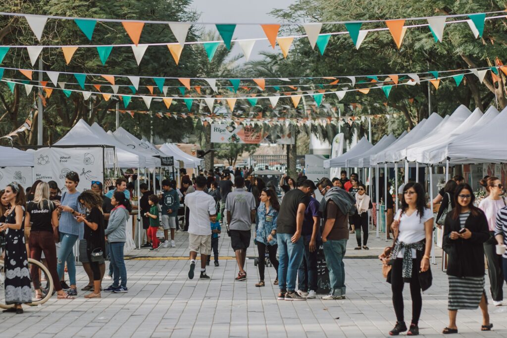 Besucher gehen bei einem Straßenfest zwischen Zelten und Ständen entlang