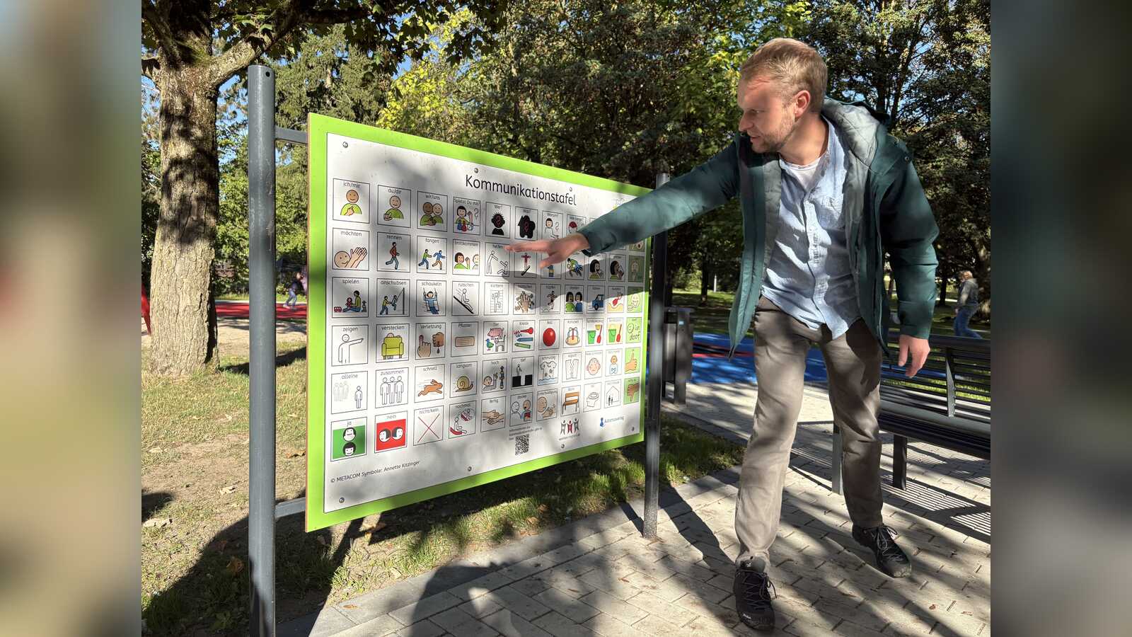 Maximilian Reick von der Stadt Dülmen stellt die Kommunikationstafel mit Symbolen und Piktogrammen am Spielplatz vor
