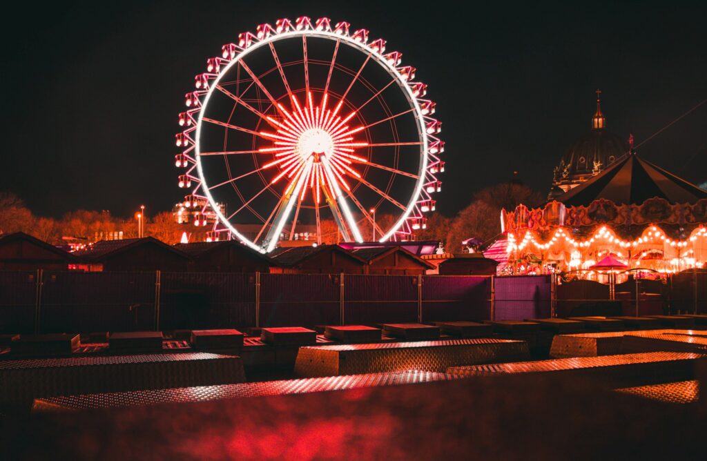 Beleuchtetes Riesenrad und Karussell auf einem Rummelplatz bei Nacht als Symbolbild für die Dreifaltigkeitskirmes Dülmen