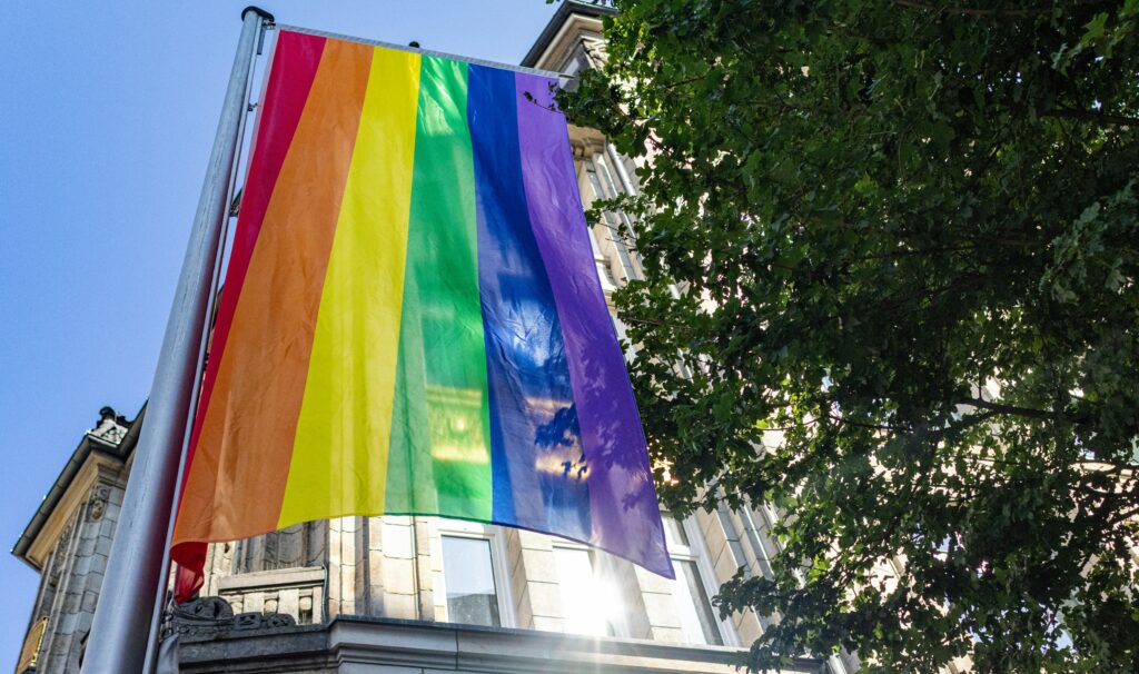 Regenbogenflagge weht vor einem Gebäude als Symbol für queere Sichtbarkeit