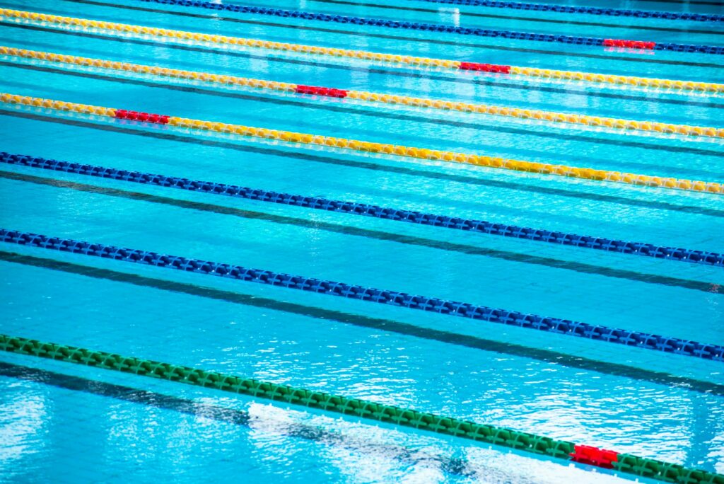 Leeres Schwimmbecken mit blauem Wasser und gespannten Bahnenleinen
