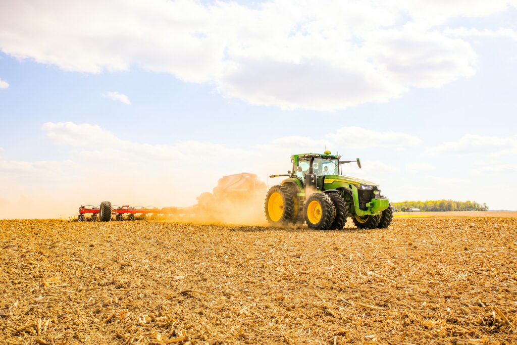 Traktor mit Anhänger bei der Feldarbeit auf einem Acker (Symbolbild)