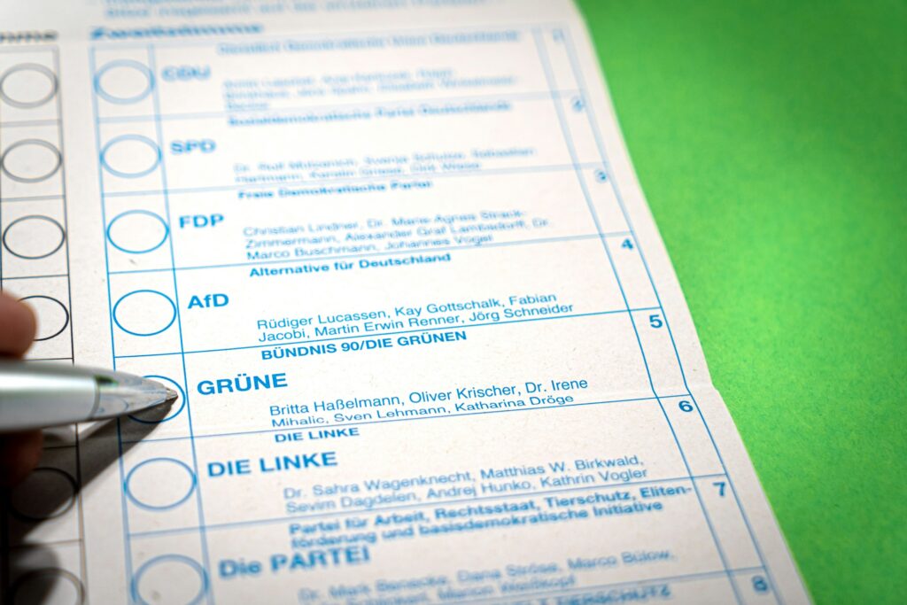 Stimmzettel wird in eine Wahlurne geworfen (Symbolbild)