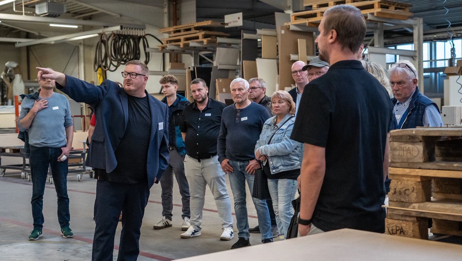 Ein Vertreter der Kuiter GmbH & Co. KG führt Teilnehmende des Unternehmertreffens durch die Werkstatt für Innenausbau