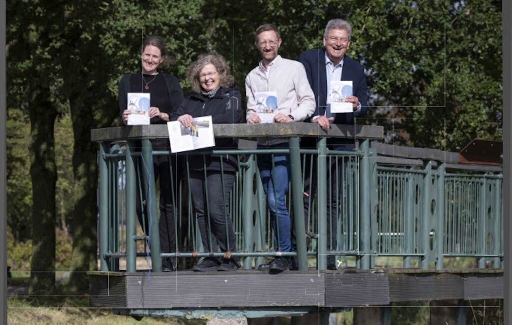 Vier Personen stehen mit Heften auf einer Brücke über die Hase an der Bifurkation in Melle-Gesmold
