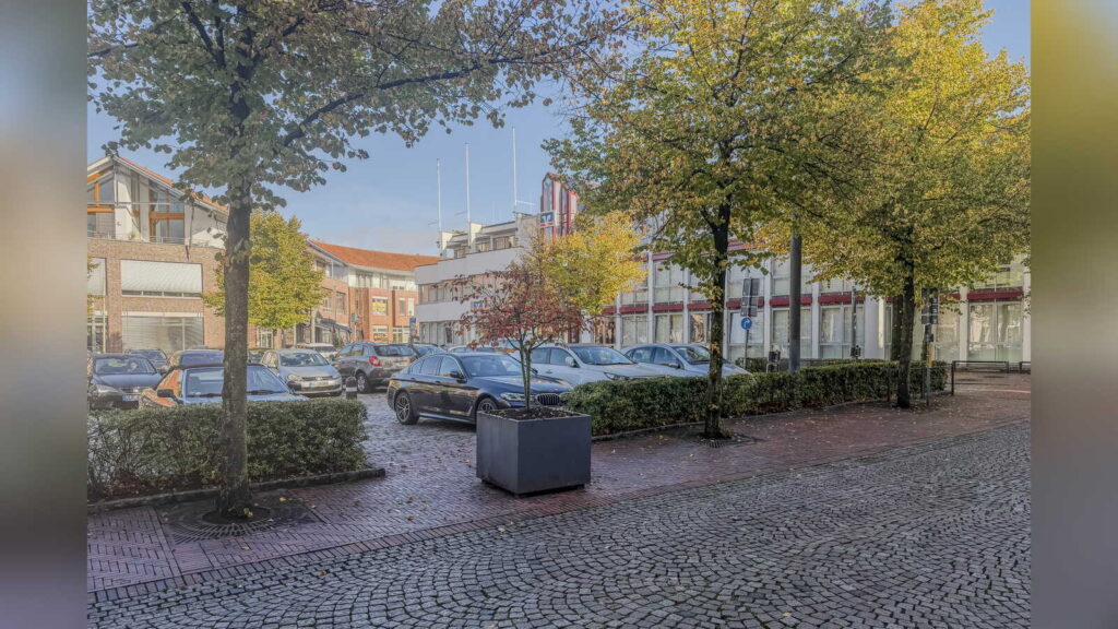 Pierre-Braun-Platz in der Lohner Innenstadt mit Parkplätzen und Hecke vor dem Umbau