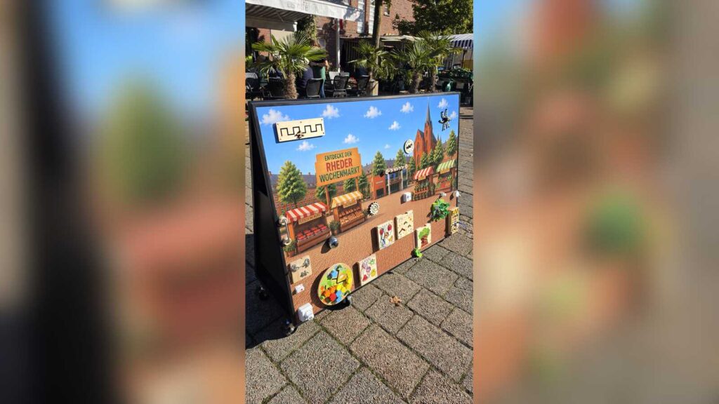 Bunte Spielewand mit gemaltem Rheder Wochenmarkt und Rathaus auf dem Rathausplatz in Rhede