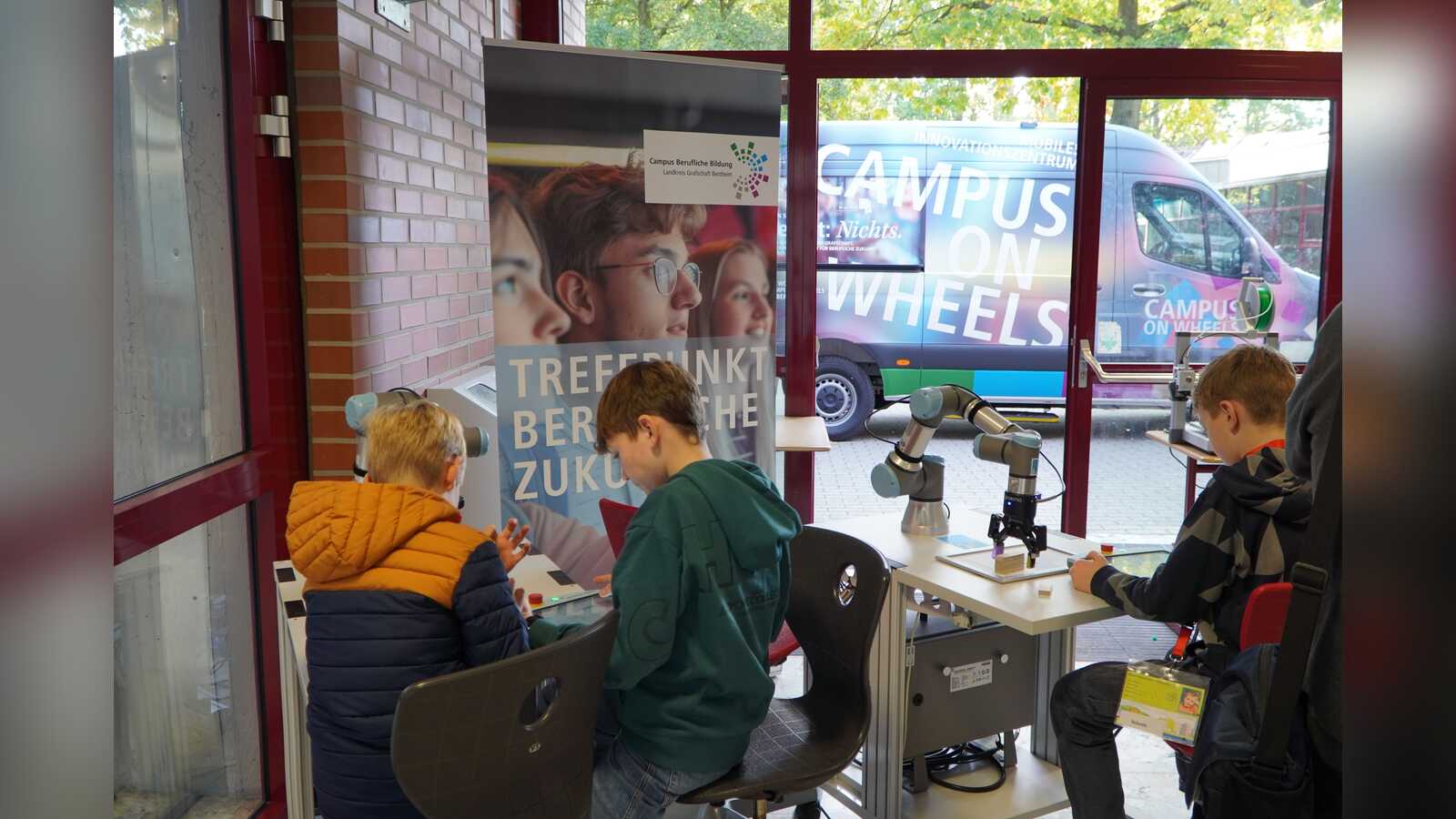 Kinder programmieren einen kollaborierenden Industrieroboter, draußen steht der Campus on Wheels