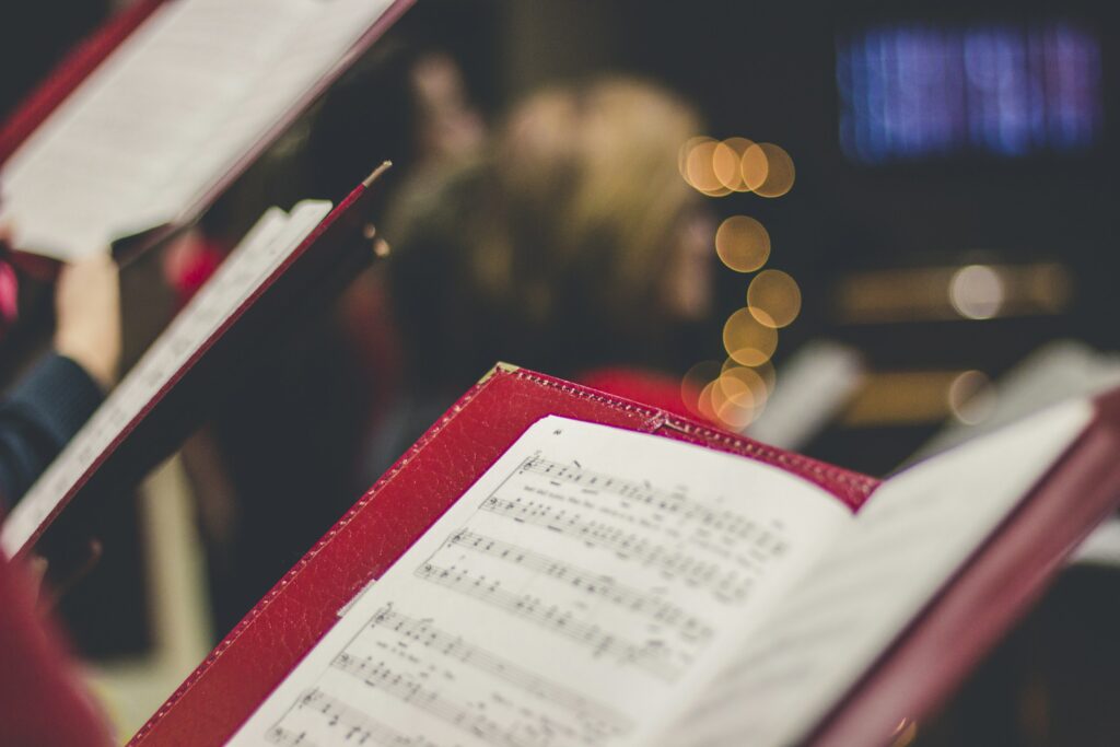 Chorsänger halten Notenblätter in den Händen