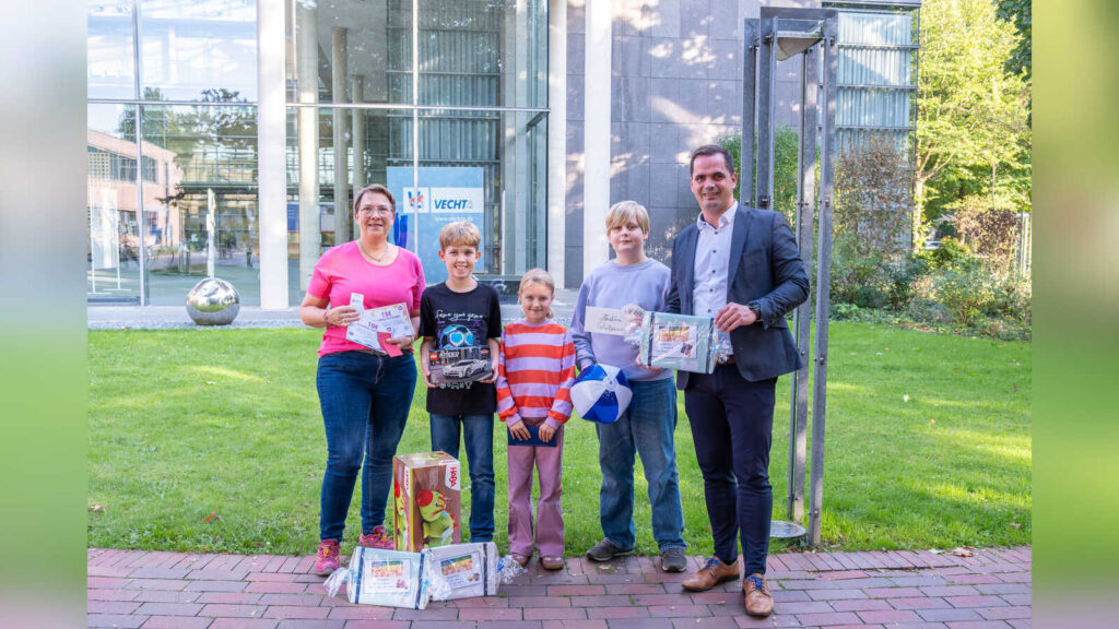 Bürgermeister Kristian Kater und Andrea Schlärmann vom Familienbüro mit drei Kindern bei der Übergabe der Hauptgewinne im Rathaus Vechta