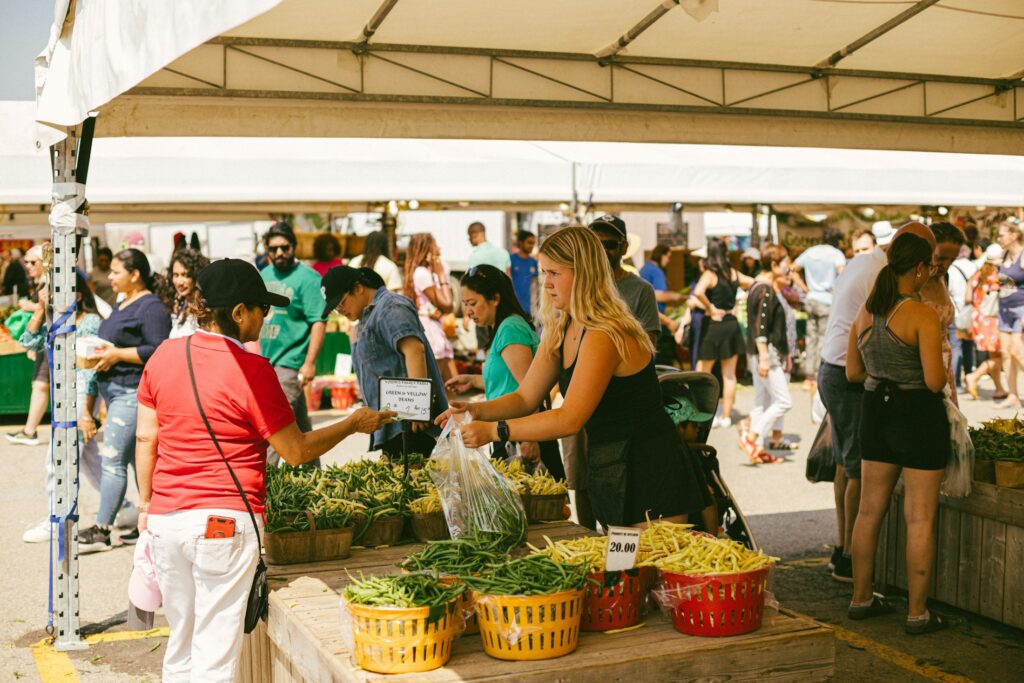 Menschen kaufen frisches Obst und Gemüse an Ständen eines Wochenmarkts