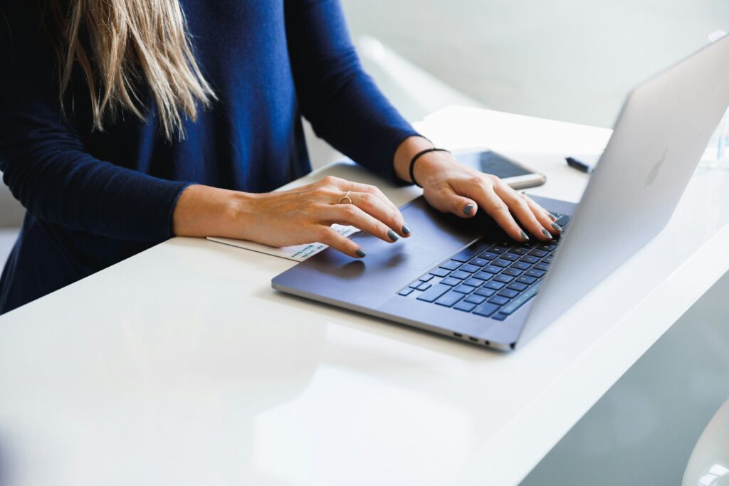 Frau in blauem Oberteil arbeitet an einem Laptop