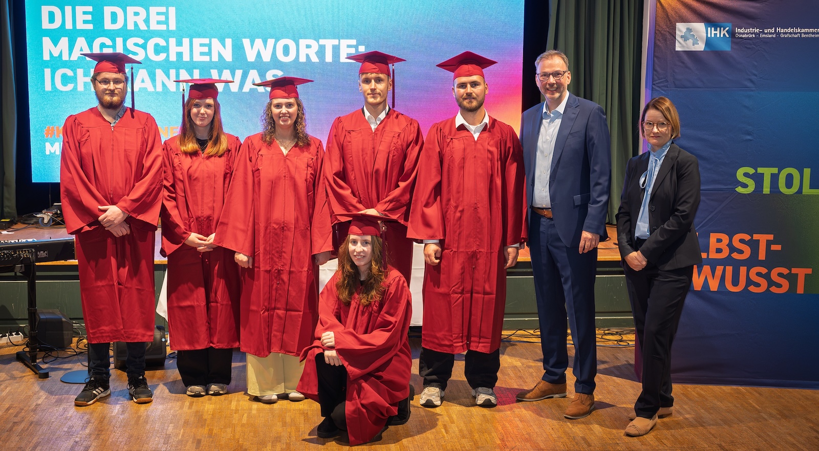 Sechs IHK-Berufsbeste aus der Grafschaft Bentheim in roten Talaren, daneben IHK-Vizepräsident Hendrik Kampmann und Juliane Hünefeld-Linkermann