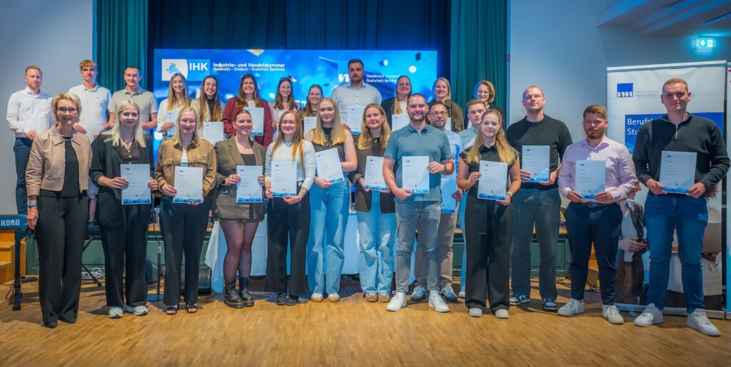 Gruppenfoto der Geprüften Wirtschaftsfachwirte mit ihren Urkunden vor der Bühne im Hofbräu an der Wilhelmshöhe in Lingen, links IHK-Vizepräsidentin Maria Borgmann