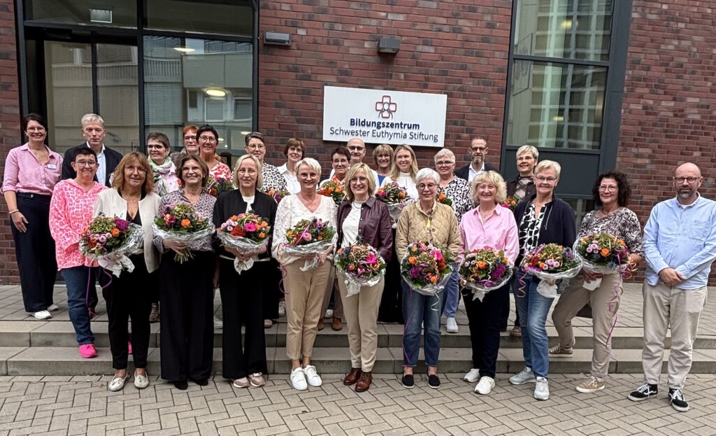 Gruppenfoto der geehrten Mitarbeiterinnen mit Blumensträußen vor dem Bildungszentrum Schwester Euthymia Stiftung