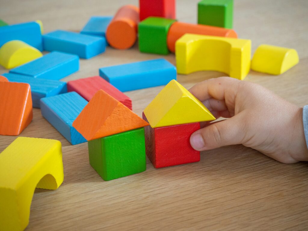 Kinderhand stapelt bunte Holzbausteine
