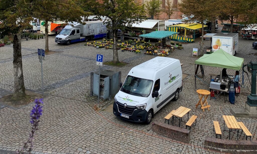 Marktstände und Verkaufswagen auf dem baumbestandenen Marktplatz in Norden, im Hintergrund die Ludgerikirche