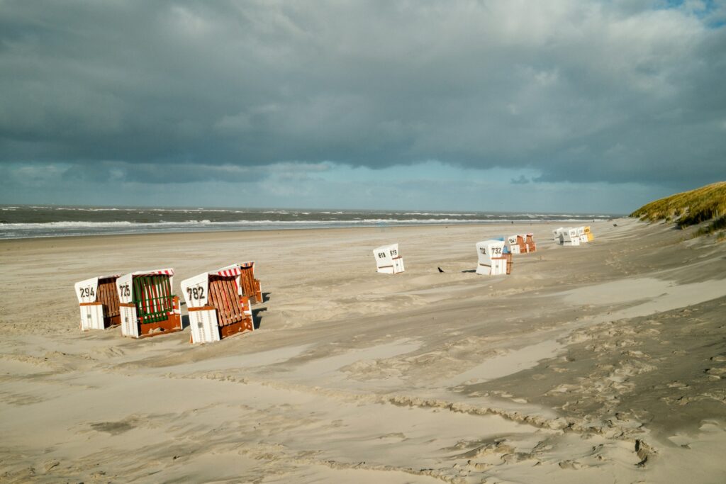 Strandkörbe an einem Sandstrand an der Nordsee unter bewölktem Himmel
