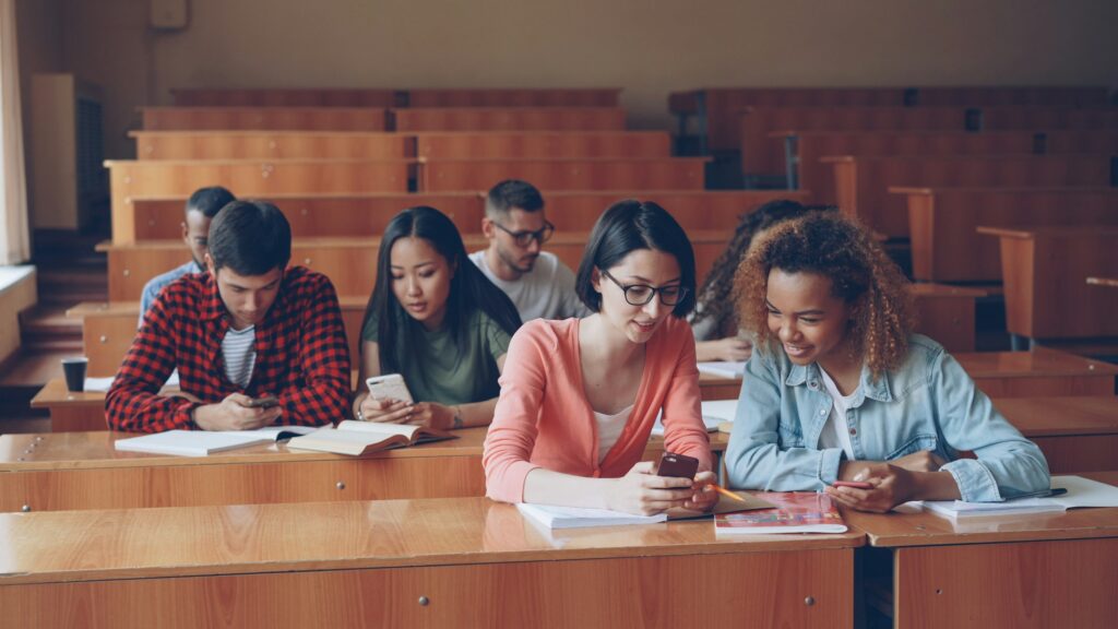 Studierende sitzen an Tischen in einem hellen Hörsaal
