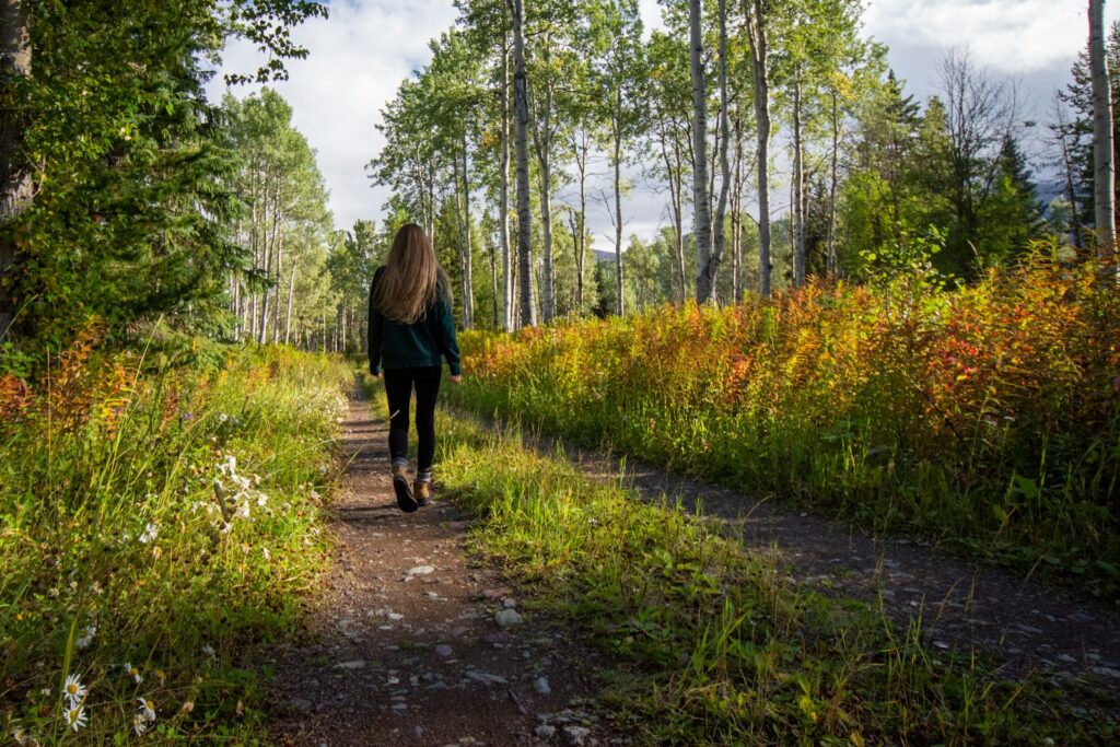 Frau geht auf einem Weg durch eine grüne Parklandschaft (Symbolbild)