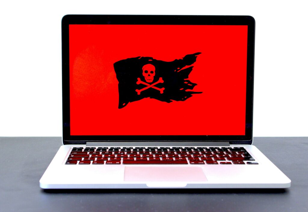 Laptop mit Totenkopf-Symbol auf rotem Bildschirm als Zeichen für einen Hackerangriff