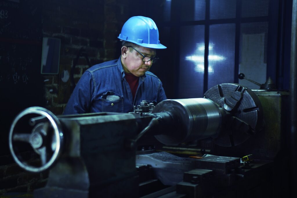 Metallarbeiter an einer Maschine in einer Werkhalle, Symbolbild Metall- und Elektroindustrie