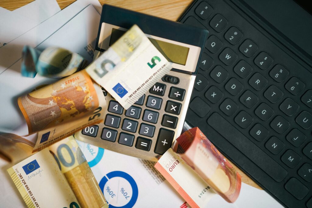 Taschenrechner, Euro-Banknoten und Tabellen mit Zahlen auf einem Schreibtisch