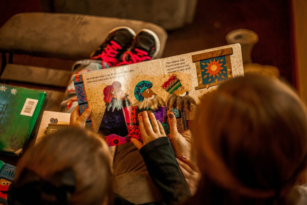 Zwei Kinder sitzen auf einem Sofa und schauen gemeinsam in ein Buch