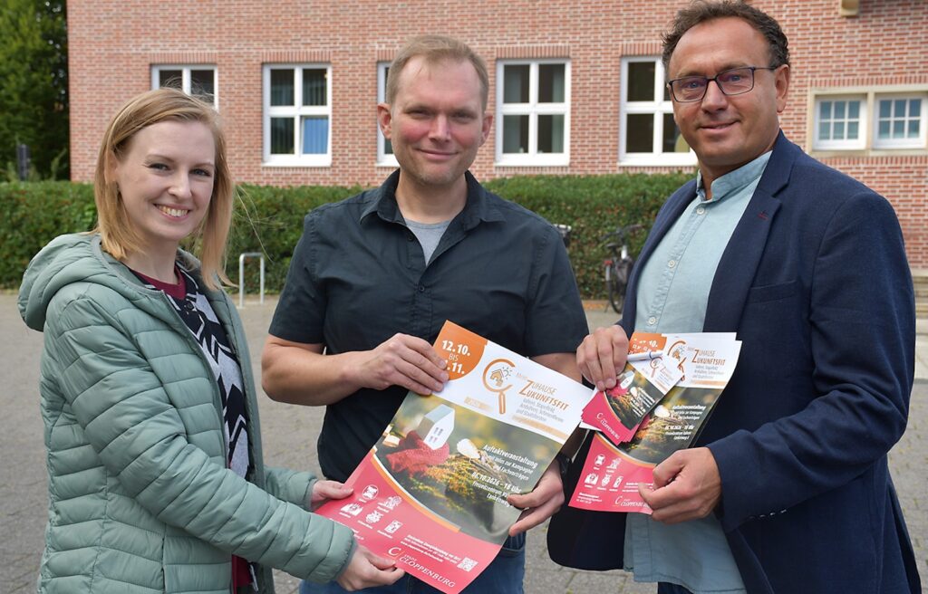 Vanessa Witt, Stefan Nienaber und Sergej Brandt halten Plakate der Kampagne Mein Zuhause zukunftsfit vor einem Backsteingebäude
