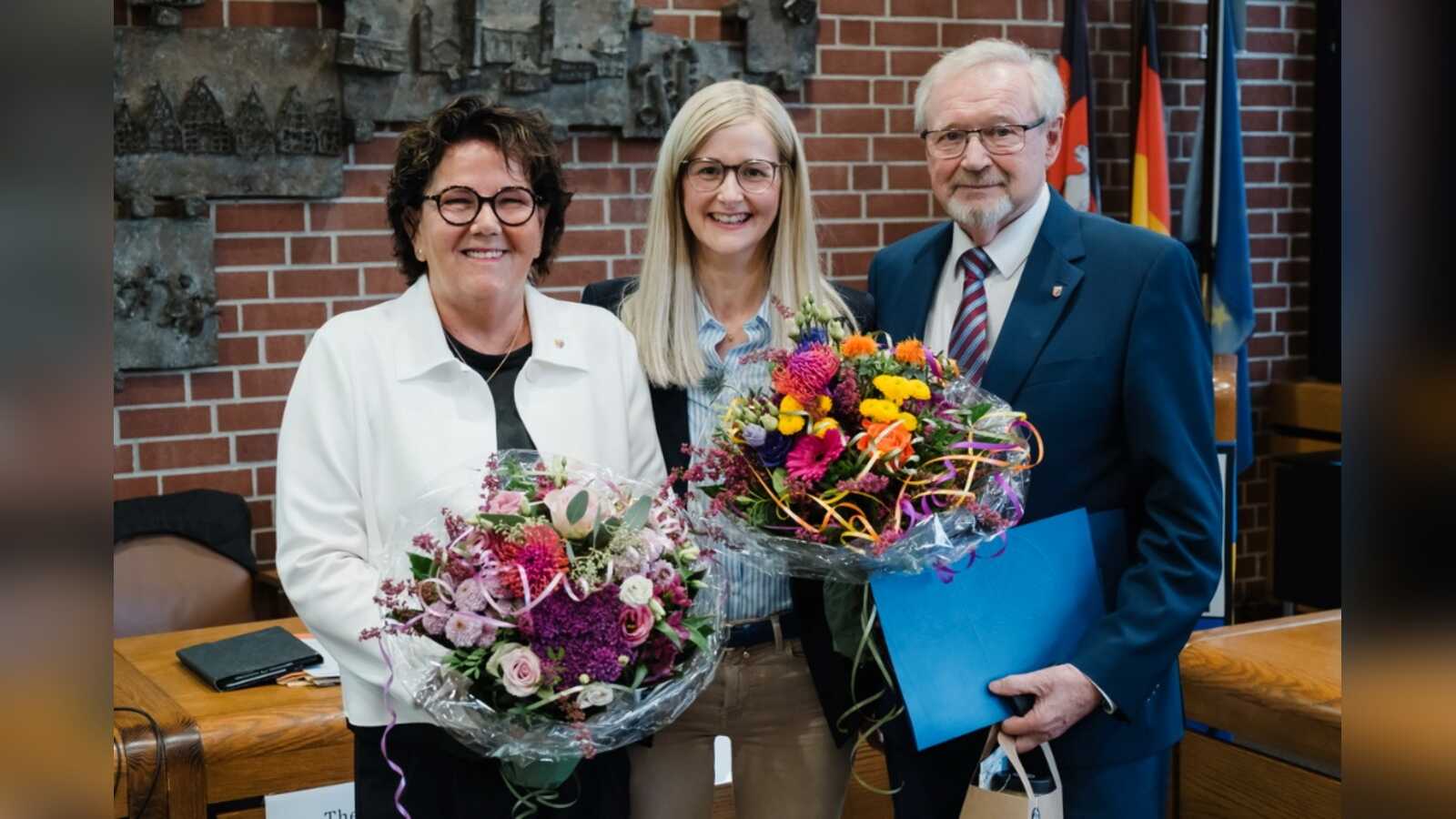 Elsbeth Schlärmann und Norbert Bockstette mit Blumensträußen, in der Mitte Bürgermeisterin Dr. Henrike Voet