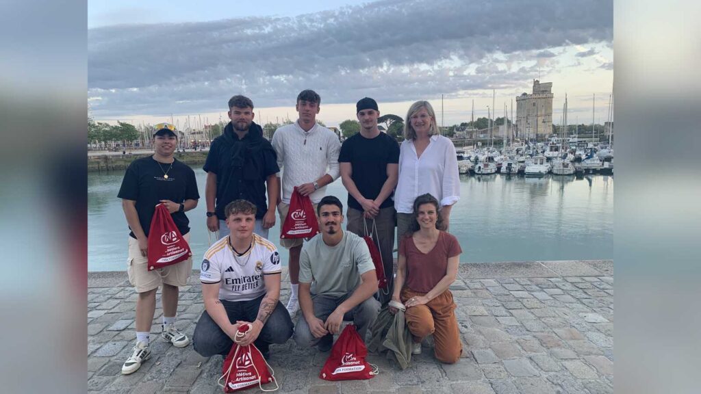 Gruppe von Auszubildenden der Handwerkskammer Oldenburg mit roten Beuteln beim Praktikum in La Rochelle