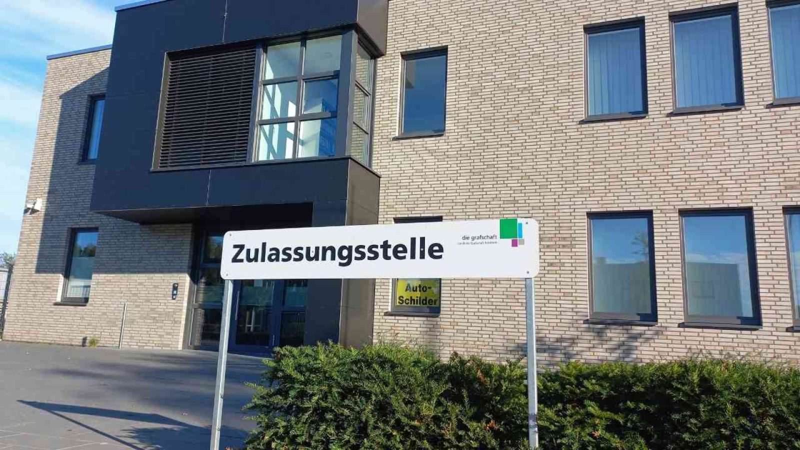 Zulassungsstelle Bürogebäude mit Schild, Herbstsonne, moderne Architektur, braune Backsteine, Fensterflächen.