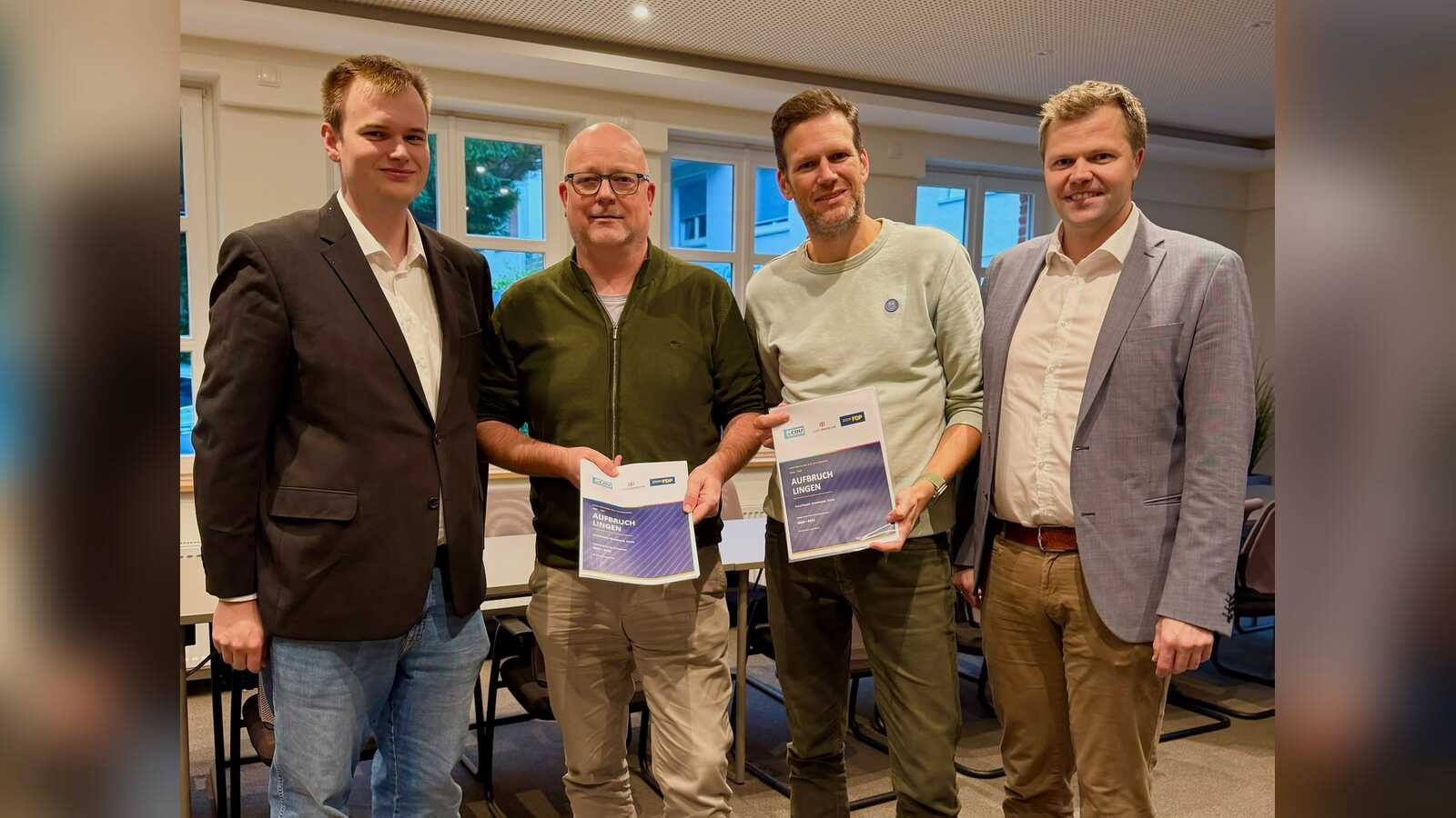 Vier Männer in einem Sitzungsraum halten die Vereinbarung „Aufbruch Lingen“ der Ratsgruppe von CDU und FDP in den Händen